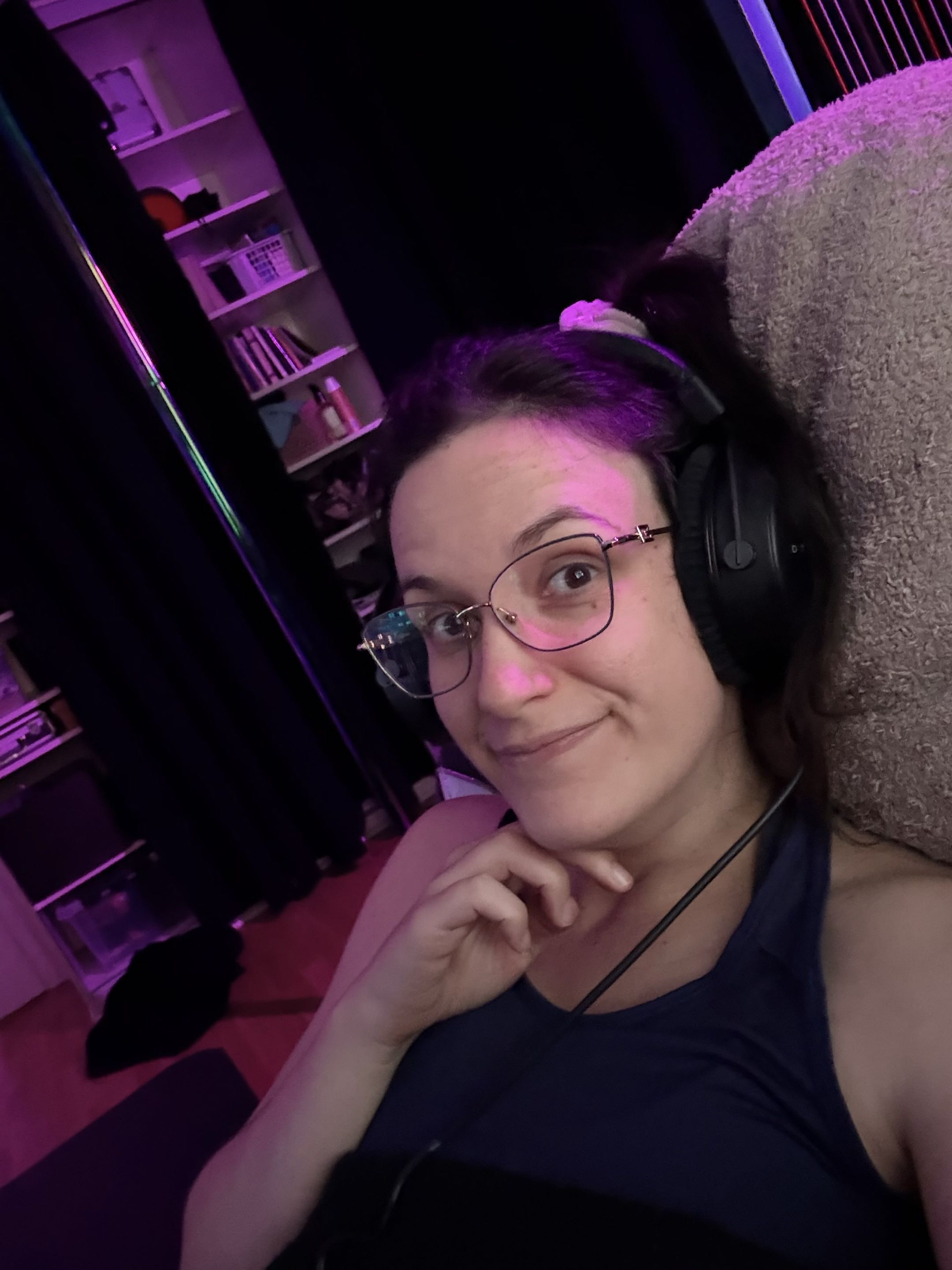 Elvann smiling in her studio, wearing glasses and headphones
